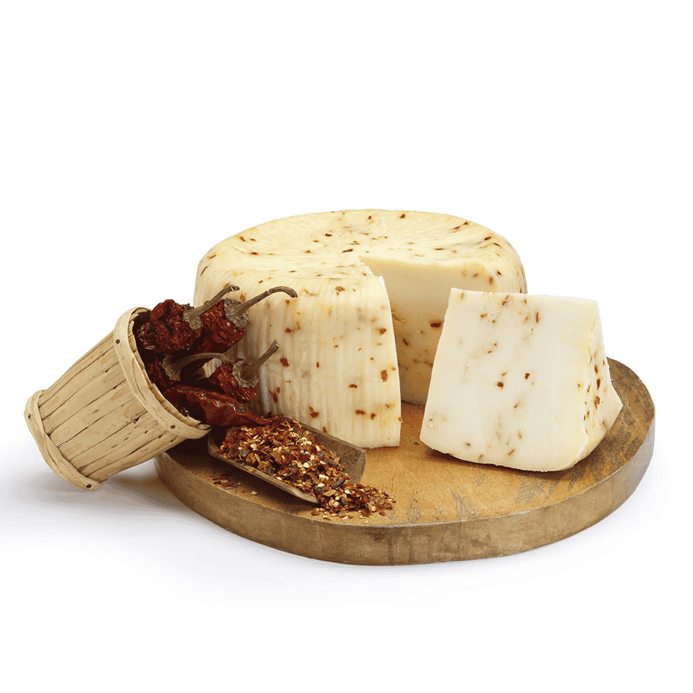 Round spicy pecorino cheese with a slice cut out on a wooden board with a small basket of dried peppers.