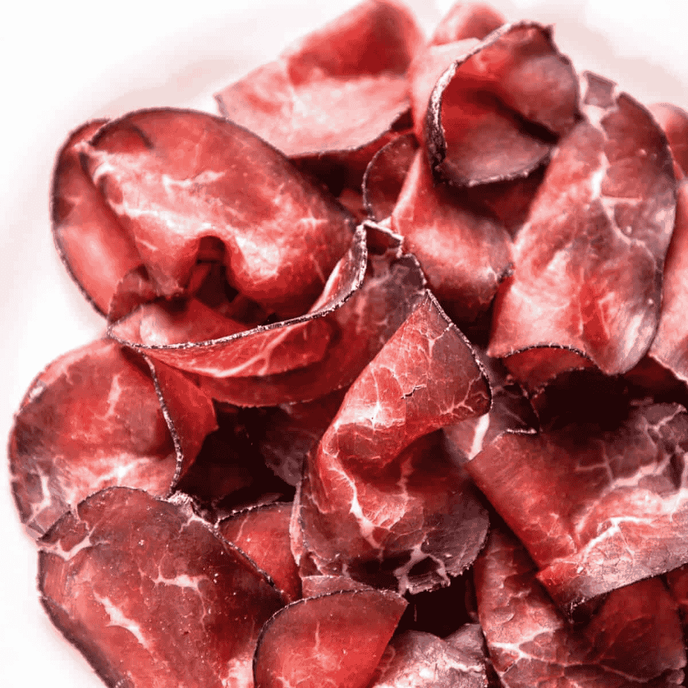 Sliced cured meat bresaola on a white background