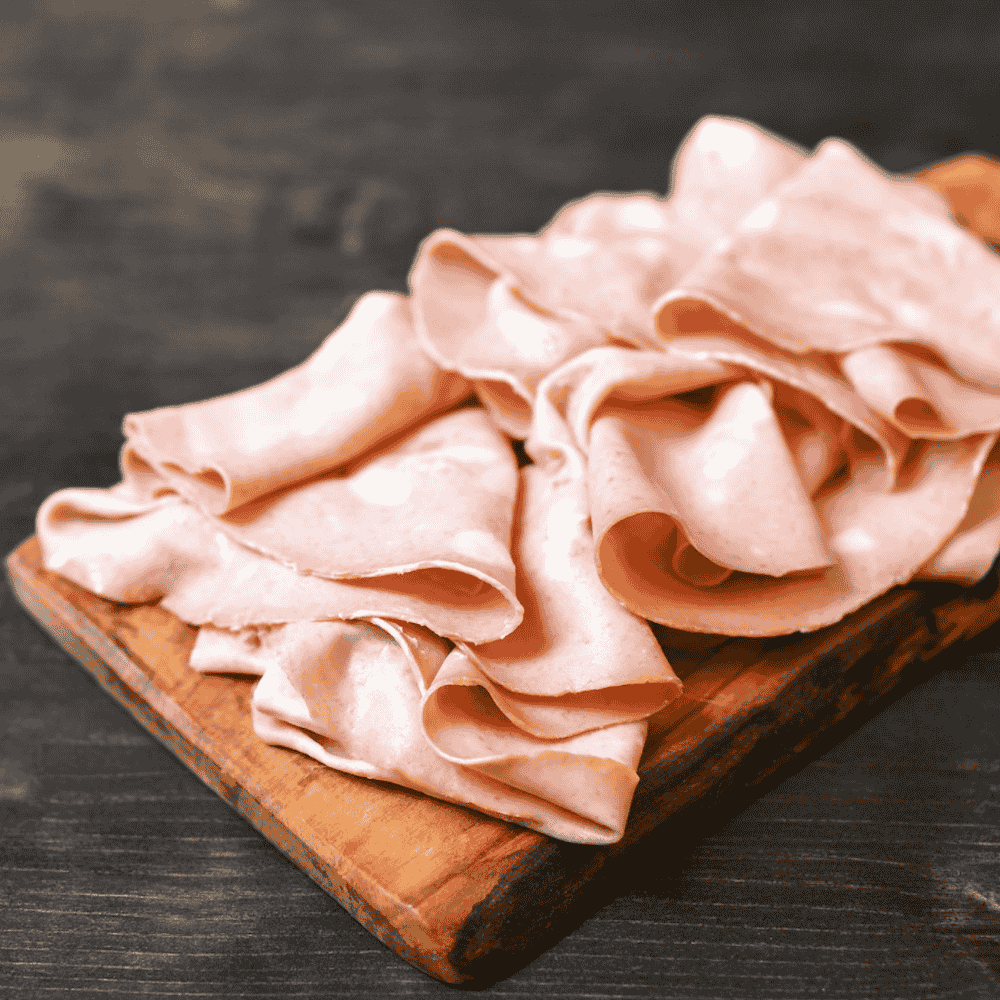 mortadella slices on a wooden cutting board with a dark background