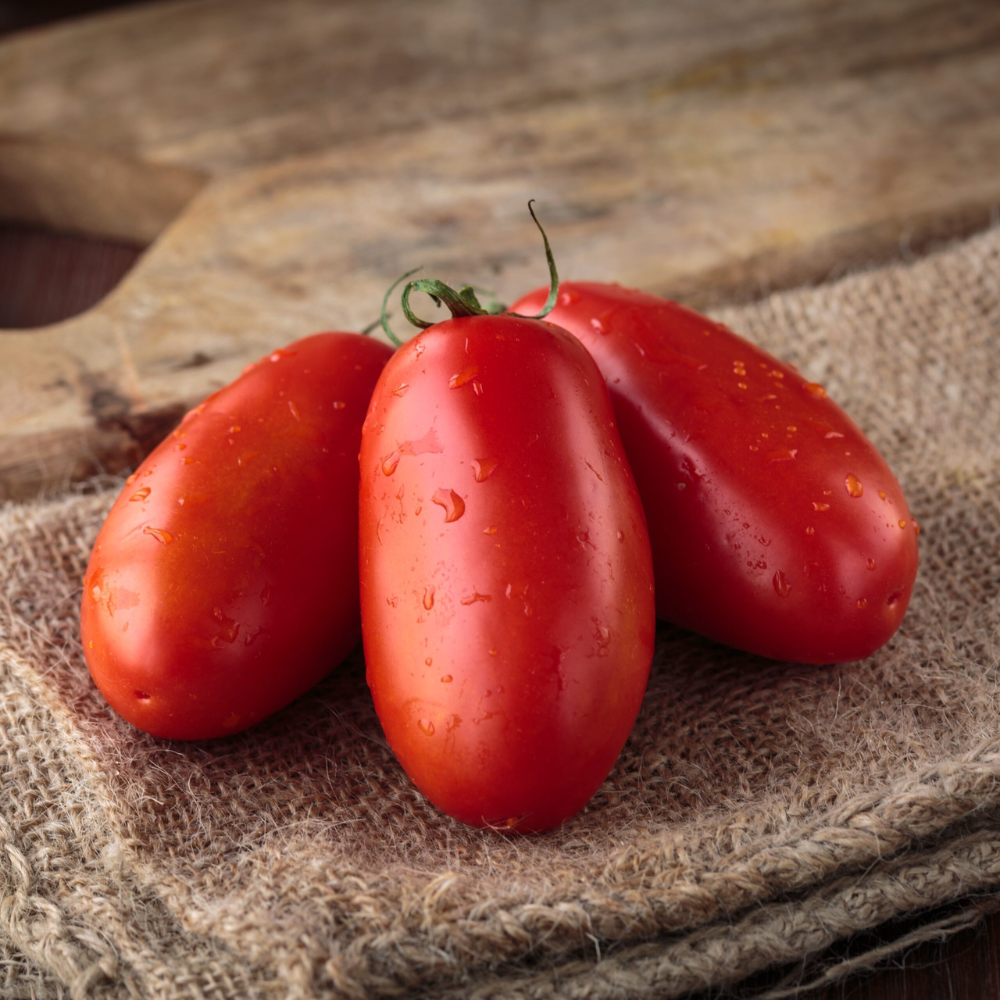 Three red san marzano tomatoes on a rustic wooden surface