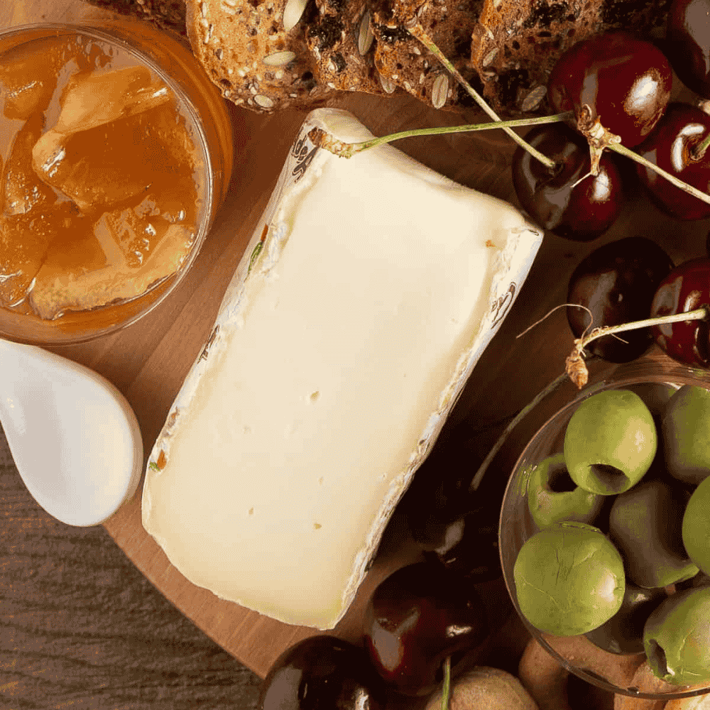 Cheeseboard with a wedge of taleggio cheese, fruits, and jam