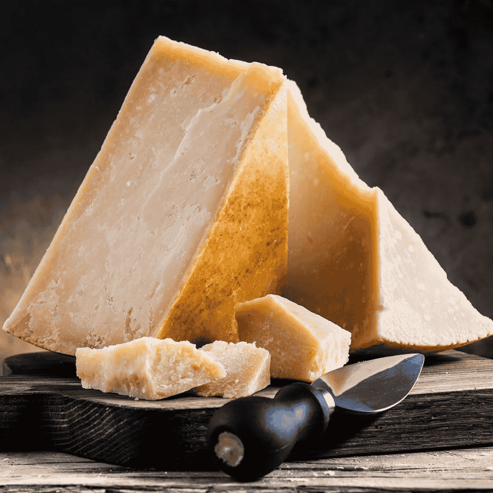 Three wedges of grana padano cheese on a wooden board with a knife.